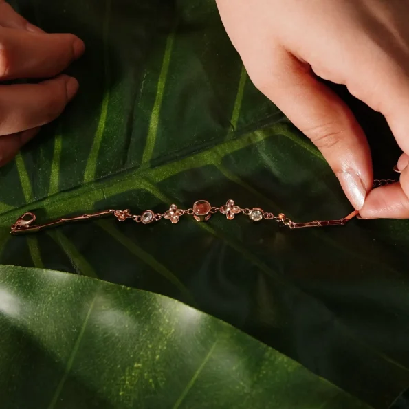 Rose gold four-leaf photo wristband placed on green leaf for a nature-inspired look