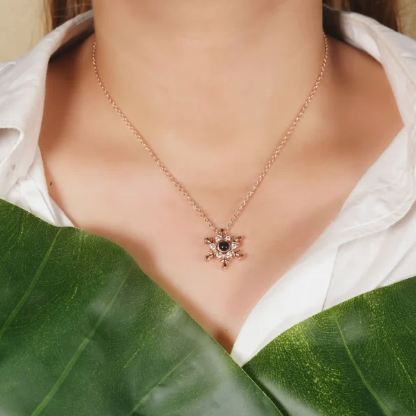Woman wearing rose gold snowflake locket, capturing a hidden memory