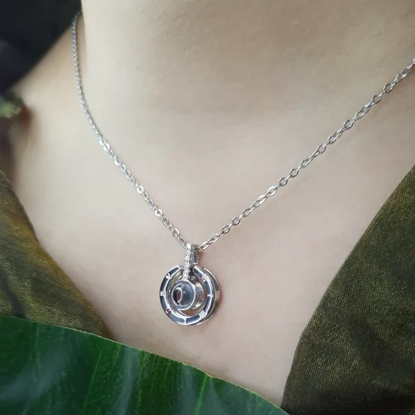 Silver roman projection necklace worn by a young woman, with the pendant at an elegant angle, adding charm to casual or formal looks.