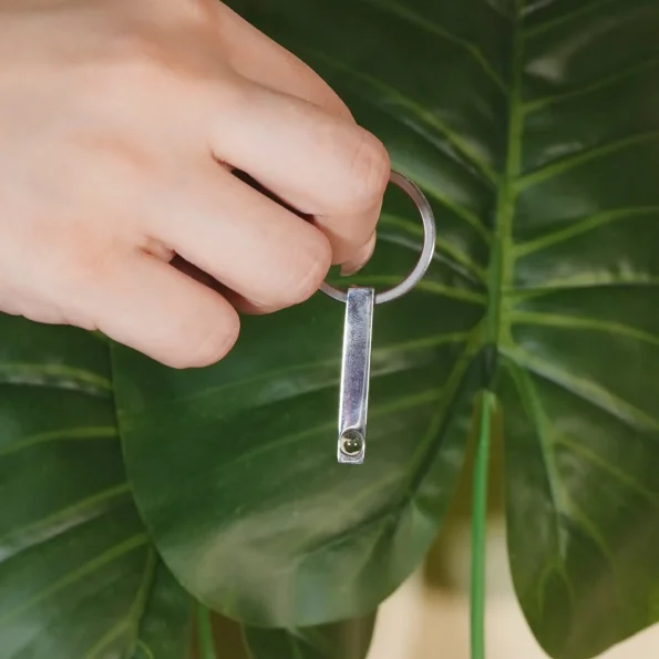 A girl holding a silver bar photo keychain with a hidden photo compartment, a perfect gift for keeping memories alive.