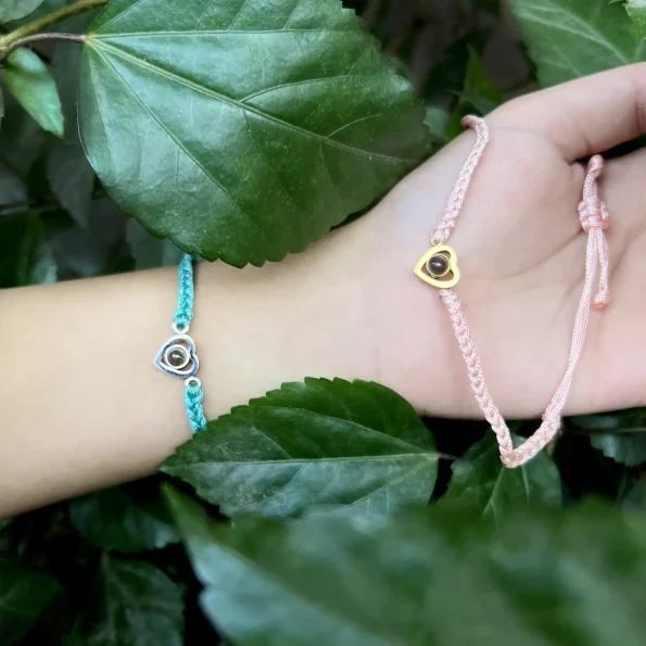 Girl holding turquoise and pink rope heart bracelets, capturing a heartfelt and meaningful moment.