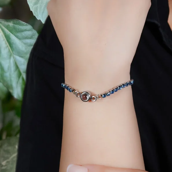 Girl wearing a blue tennis charm bracelet with hidden projection, a perfect accessory to remember special moments.