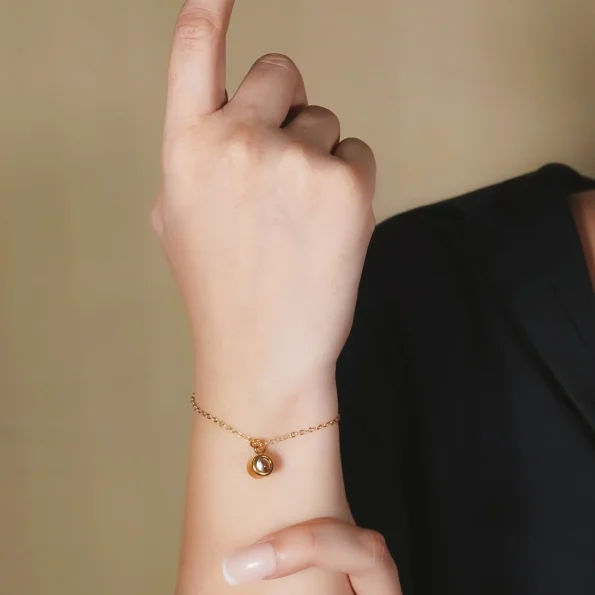 Girl wearing a gold charm bracelet, adding a touch of warmth and elegance.