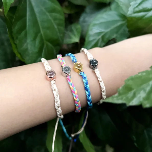 Woman wearing photo rope bracelets in rainbow wave, deep blue, and natural nostalgia, each a keepsake of cherished memories.