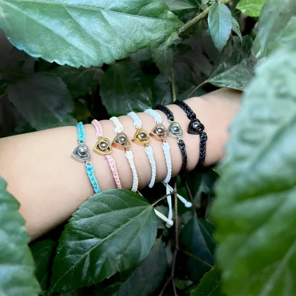 Model wearing black, turquoise, pink, beige, and white rope heart bracelets, a stylish and sentimental statement.