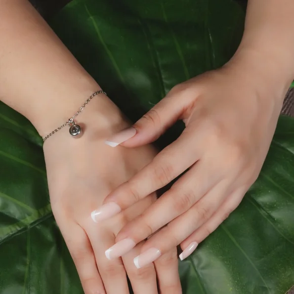 Model wearing a silver charm bracelet, exuding grace and sophistication.