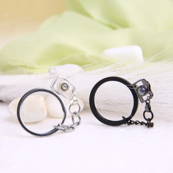Silver and black camera photo keychain with hidden projection, combining elegance with sentimental value.