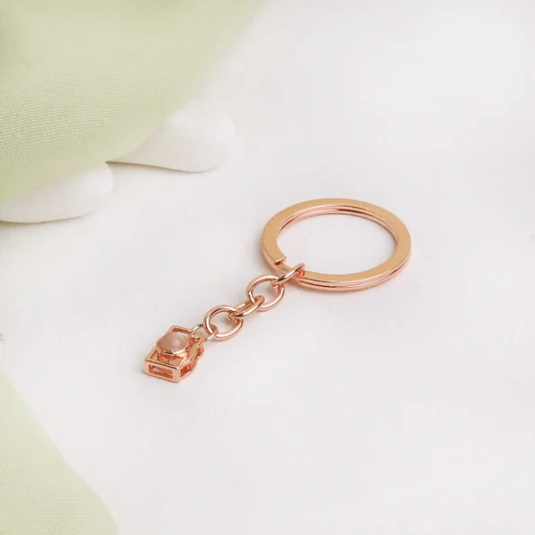 Rose gold camera photo keychain with a hidden projection, capturing memories in an elegant design.