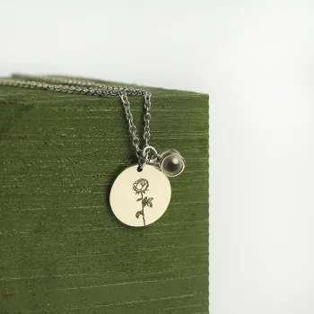 Close-up of silver birthflower photo necklace, highlighting its intricate floral design and hidden photo feature.