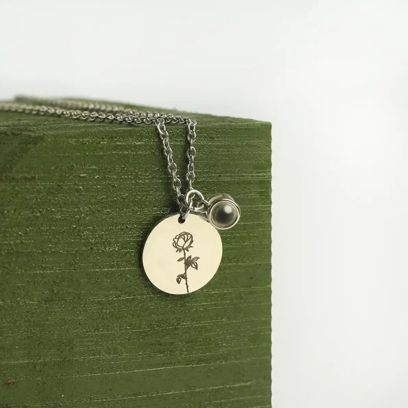 Close-up of silver birthflower photo necklace, highlighting its intricate floral design and hidden photo feature.